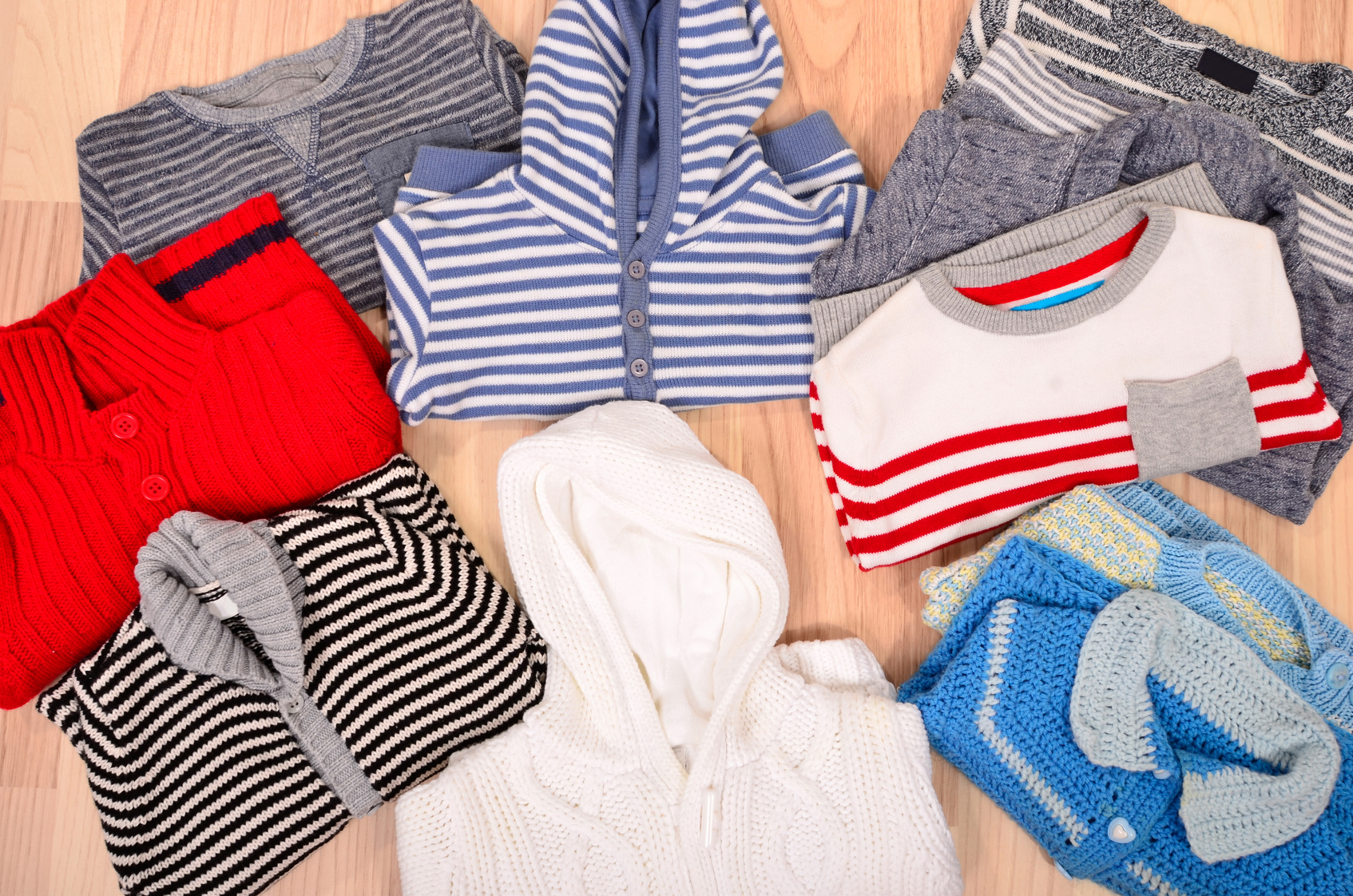 Baby clothes lying on the floor. Winter child sweaters arranged, colorful wardrobe for toddler.